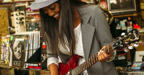 a happy woman playing a red guitar